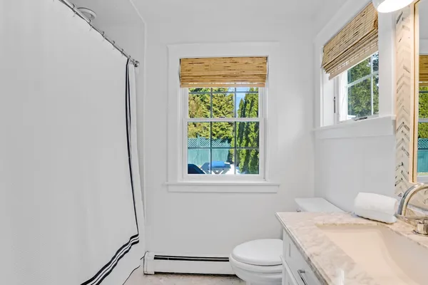 a bathroom with a granite countertop toilet a sink and a window