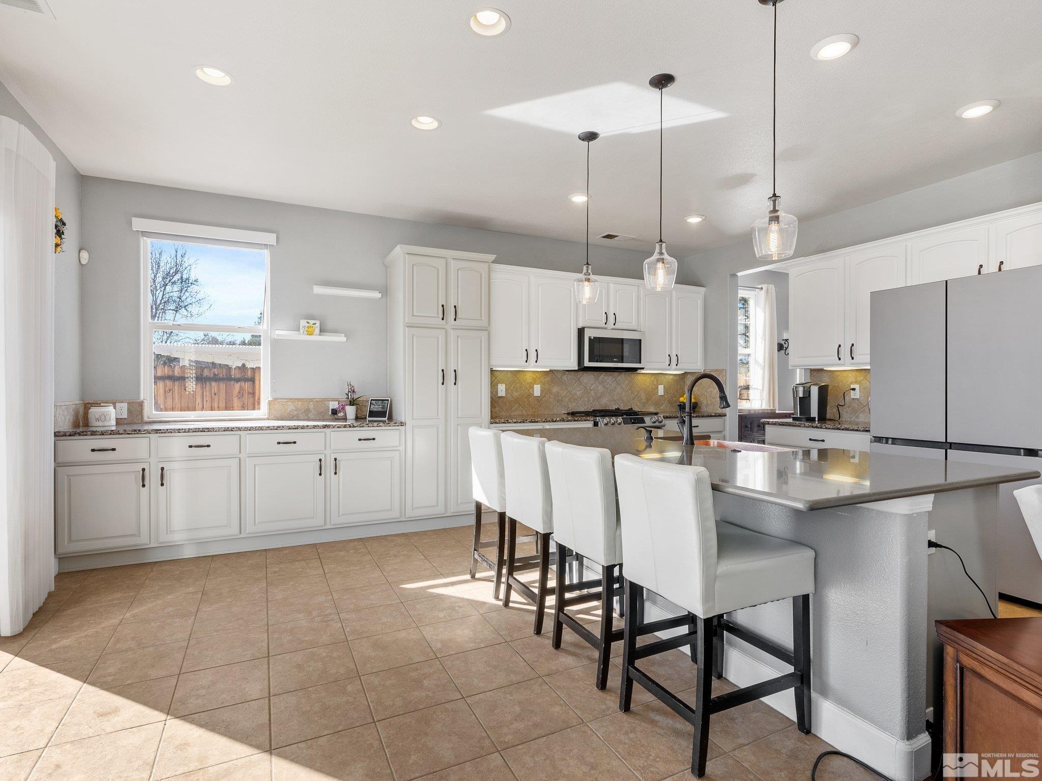3451 Weaver Place Reno, NV 89512 - Photo 12 of 40 a kitchen with stainless steel appliances kitchen island granite countertop a table chairs and a refrigerator