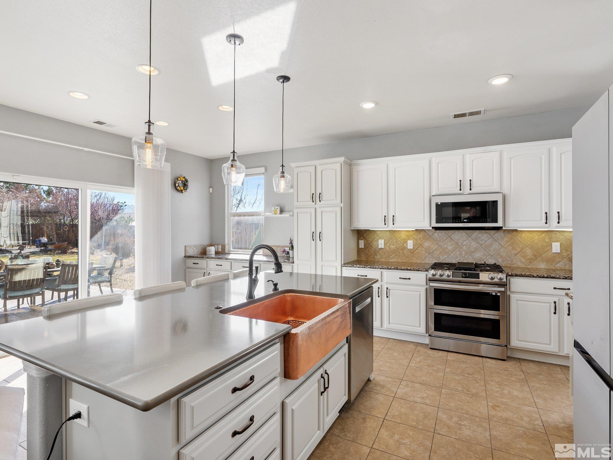 3451 Weaver Place Reno, NV 89512 - Photo 13 of 40 a kitchen with stainless steel appliances granite countertop a stove a sink a oven a dining table and chairs