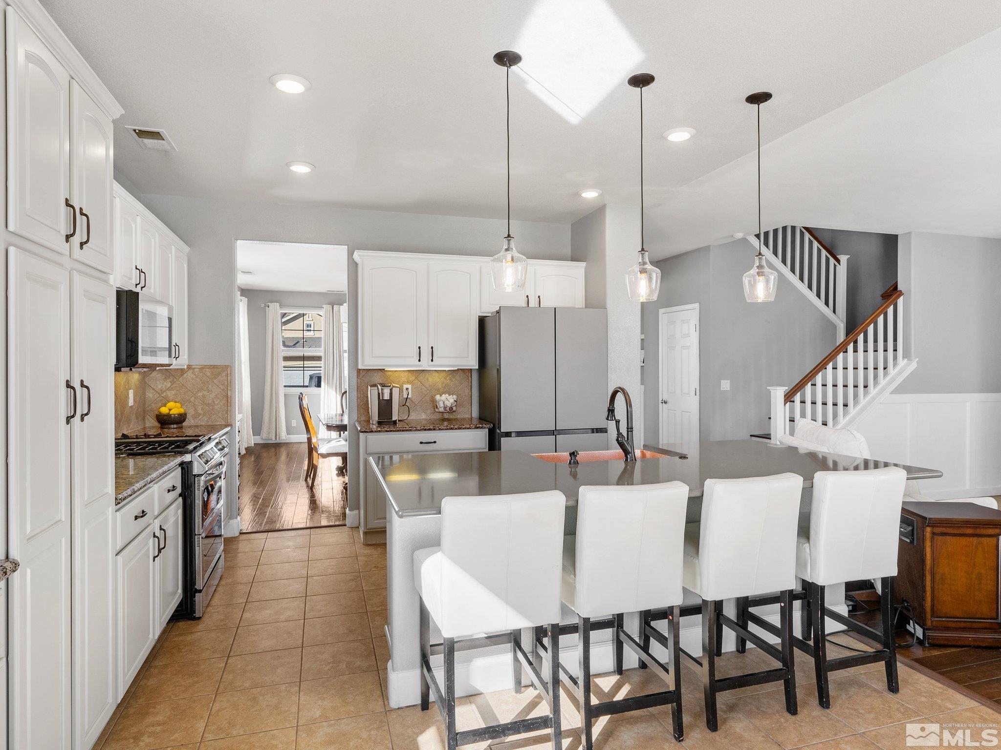 3451 Weaver Place Reno, NV 89512 - Photo 10 of 40 a kitchen with stainless steel appliances kitchen island granite countertop a table chairs and a refrigerator