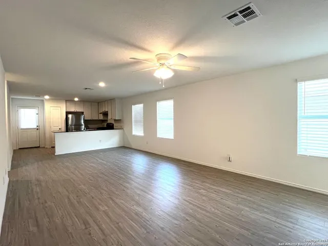 a view of a livingroom with a kitchen stove wooden cabinets and a window