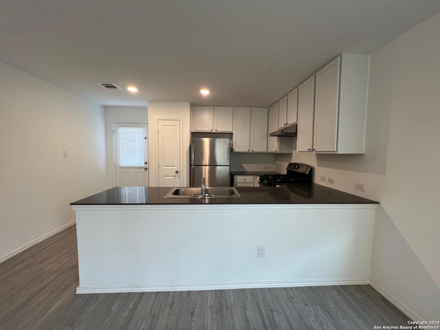 9928 Leeds Wheel San Antonio, TX 78254 - Photo 4 of 11 a kitchen with stainless steel appliances granite countertop a sink a stove and a refrigerator with wooden floor