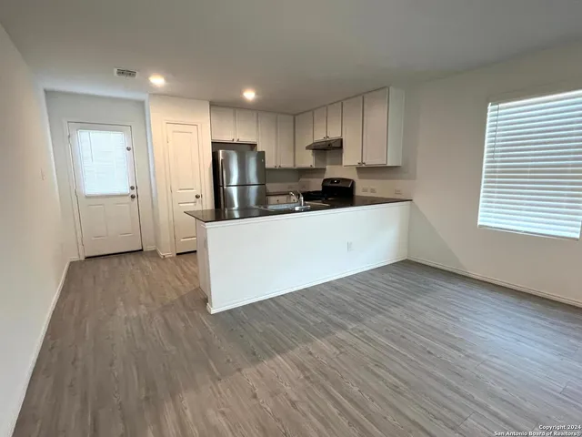 a large white kitchen with wooden floors and stainless steel appliances