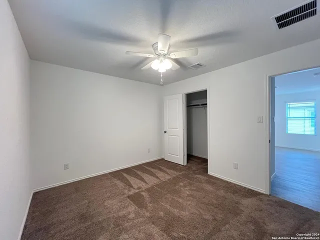 a view of an empty room and chandelier fan