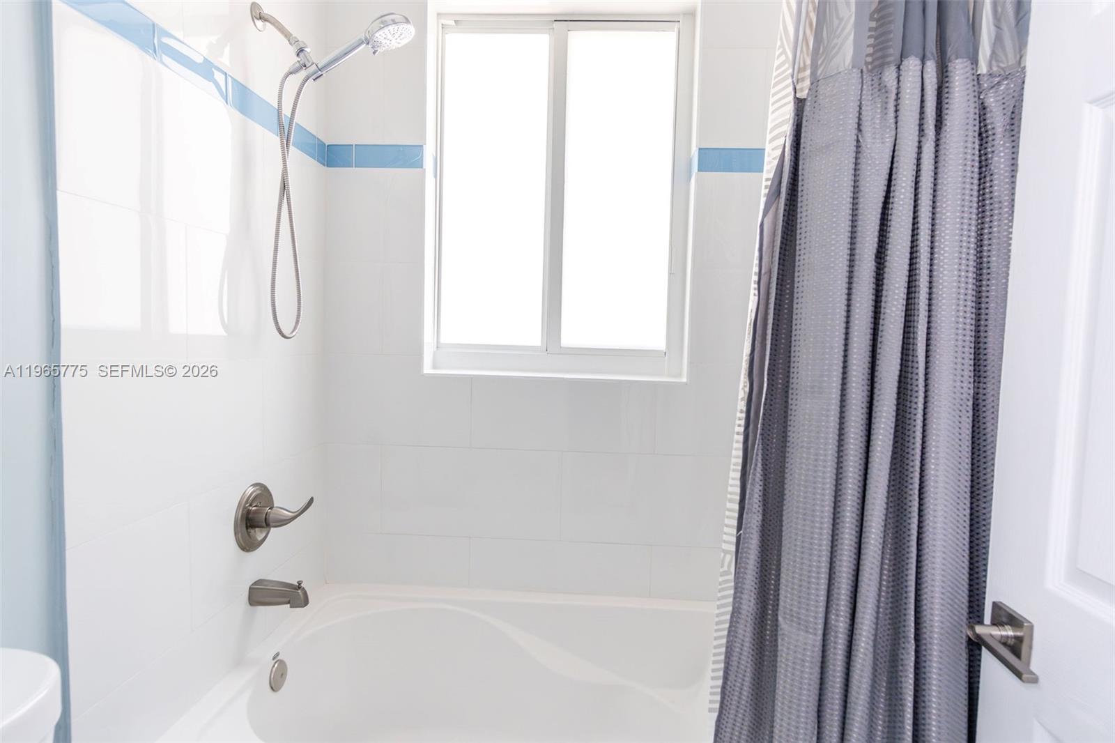 12523 Southwest 121st Way Miami, FL 33186 - Photo 41 of 56 a bathroom with a bathtub a shower and a window