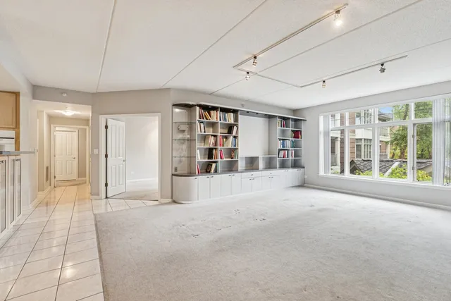 a view of an empty room with a window and a kitchen