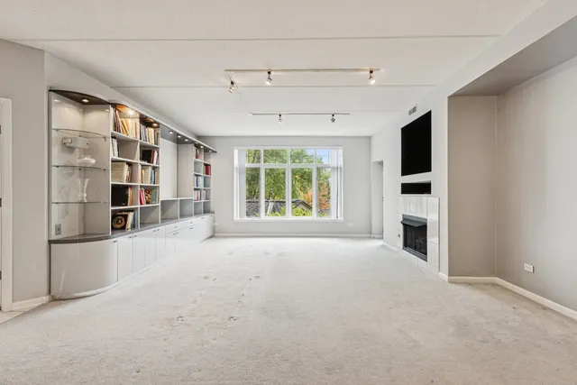 a view of an empty room with a window and fire place