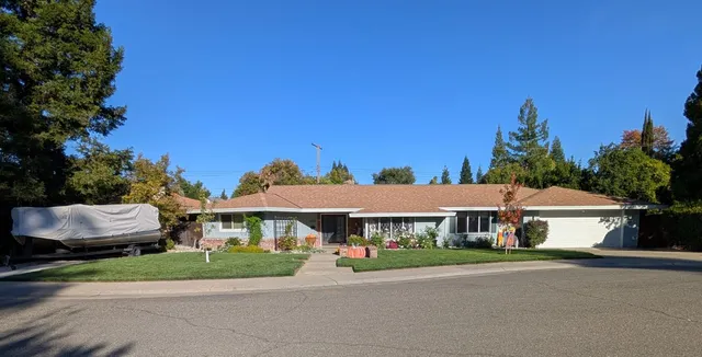 a front view of a house with a garden and trees