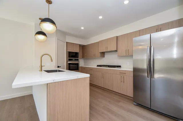 a kitchen with stainless steel appliances granite countertop a sink a refrigerator and a stove