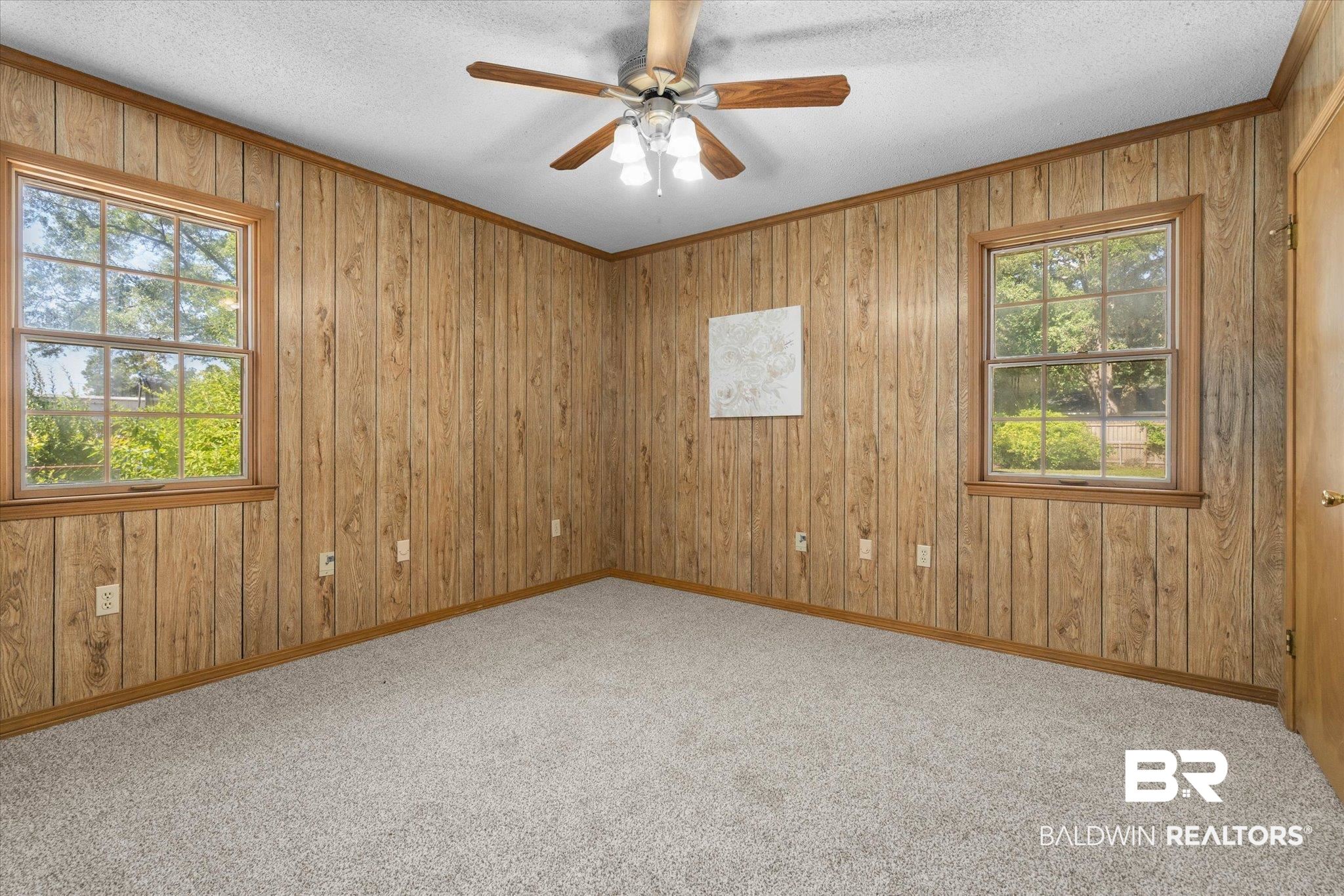 5503 Darring Street Satsuma, AL 36572 - Photo 17 of 31 Carpeted spare room with wooden walls, ornamental molding, a ceiling fan, and a textured ceiling