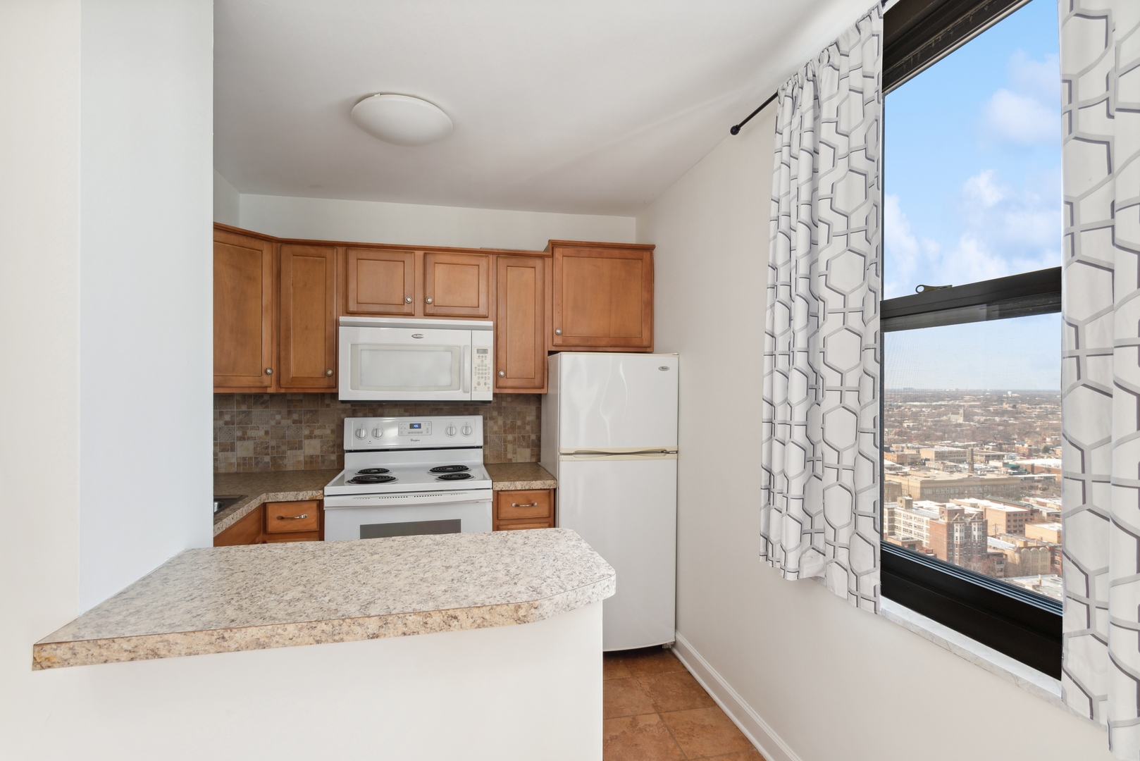 5701 North Sheridan Road, Unit 30D Chicago, IL 60660 - Photo 9 of 16 a kitchen with a refrigerator a stove a microwave and cabinets