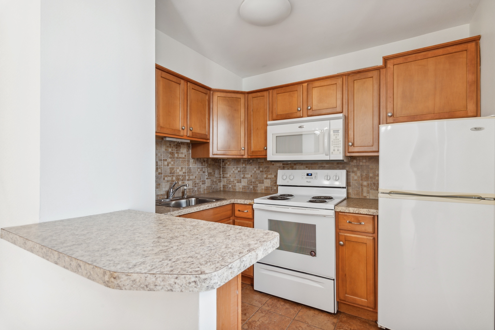 5701 North Sheridan Road, Unit 30D Chicago, IL 60660 - Photo 10 of 16 a kitchen with granite countertop white cabinets and white appliances