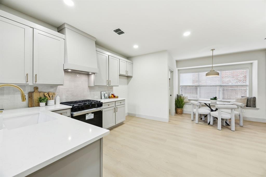 2437 Clear Field Drive Plano, TX 75025 - Photo 6 of 38 a kitchen with stainless steel appliances granite countertop a stove top oven a sink a dining table and chairs with white cabinets