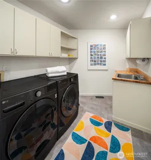 a utility room with stainless steel appliances cabinets and a rug