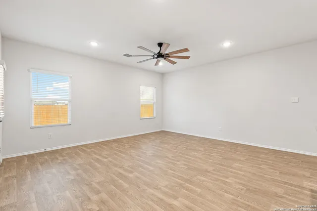 a view of empty room with wooden floor and fan