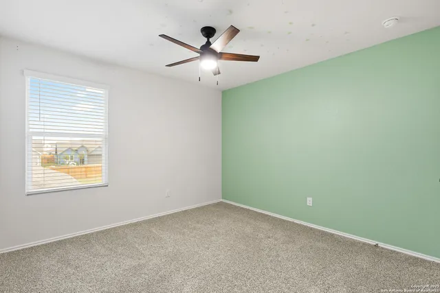 an empty room with a ceiling fan and a window