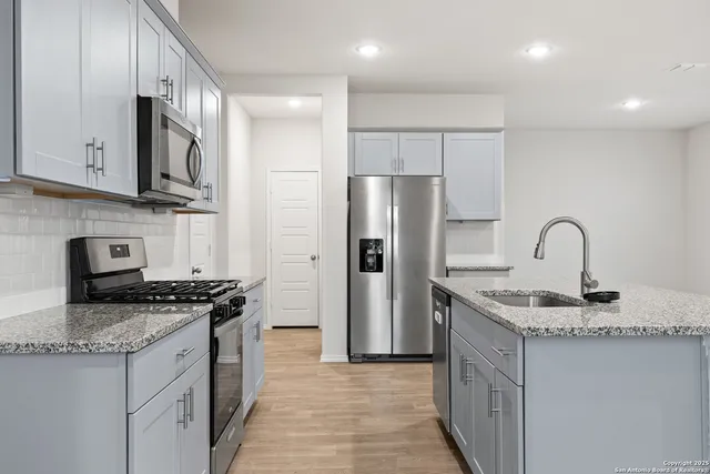 a kitchen with stainless steel appliances granite countertop a refrigerator and a stove top oven