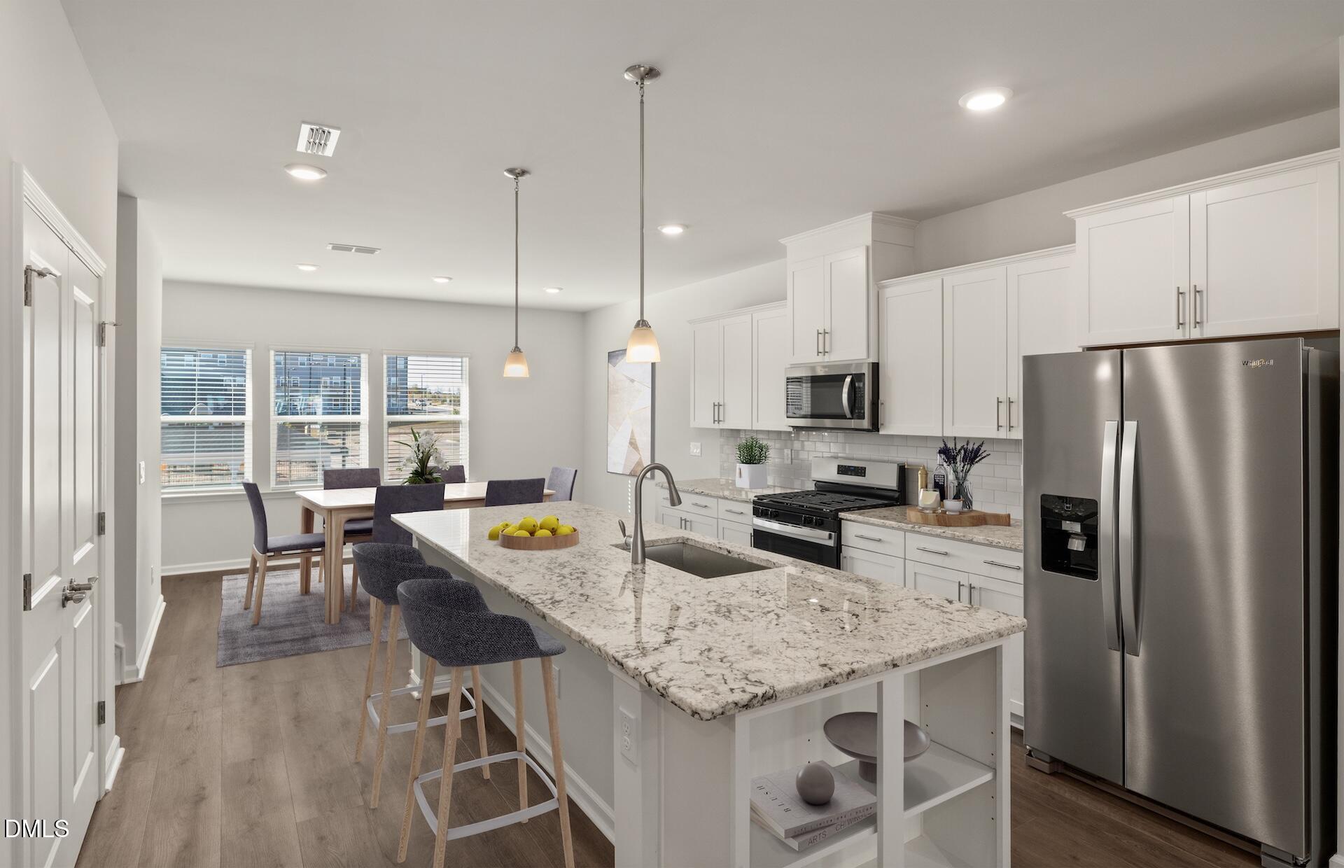 918 Fearless Road Durham, NC 27703 - Photo 3 of 25 a kitchen with granite countertop kitchen island stainless steel appliances a refrigerator a stove a sink a dining table and chairs