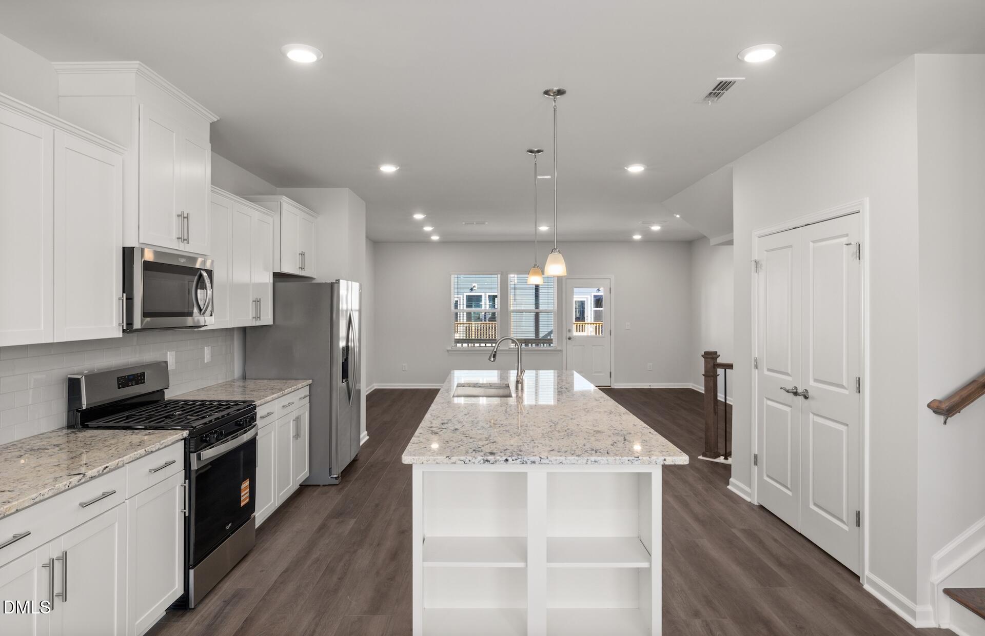 918 Fearless Road Durham, NC 27703 - Photo 6 of 25 a kitchen with stainless steel appliances kitchen island granite countertop a refrigerator a stove a sink and a oven with wooden floor