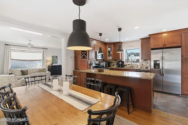 a open kitchen with stainless steel appliances granite countertop a stove a refrigerator a kitchen island a dining table and chairs