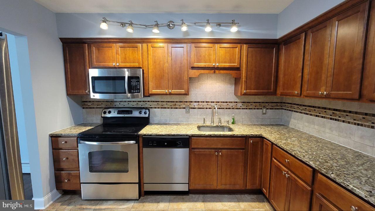 1575 West Street Road, Unit 832 Warminster, PA 18974 - Photo 2 of 14 a kitchen with stainless steel appliances granite countertop a sink stove and microwave