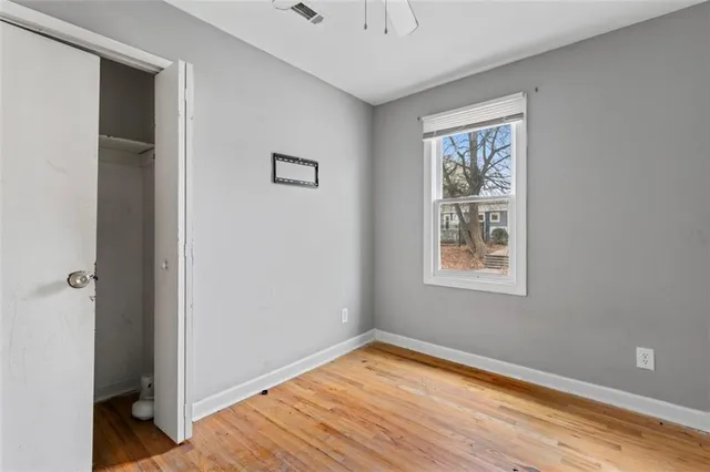 a view of empty room with wooden floor and fan