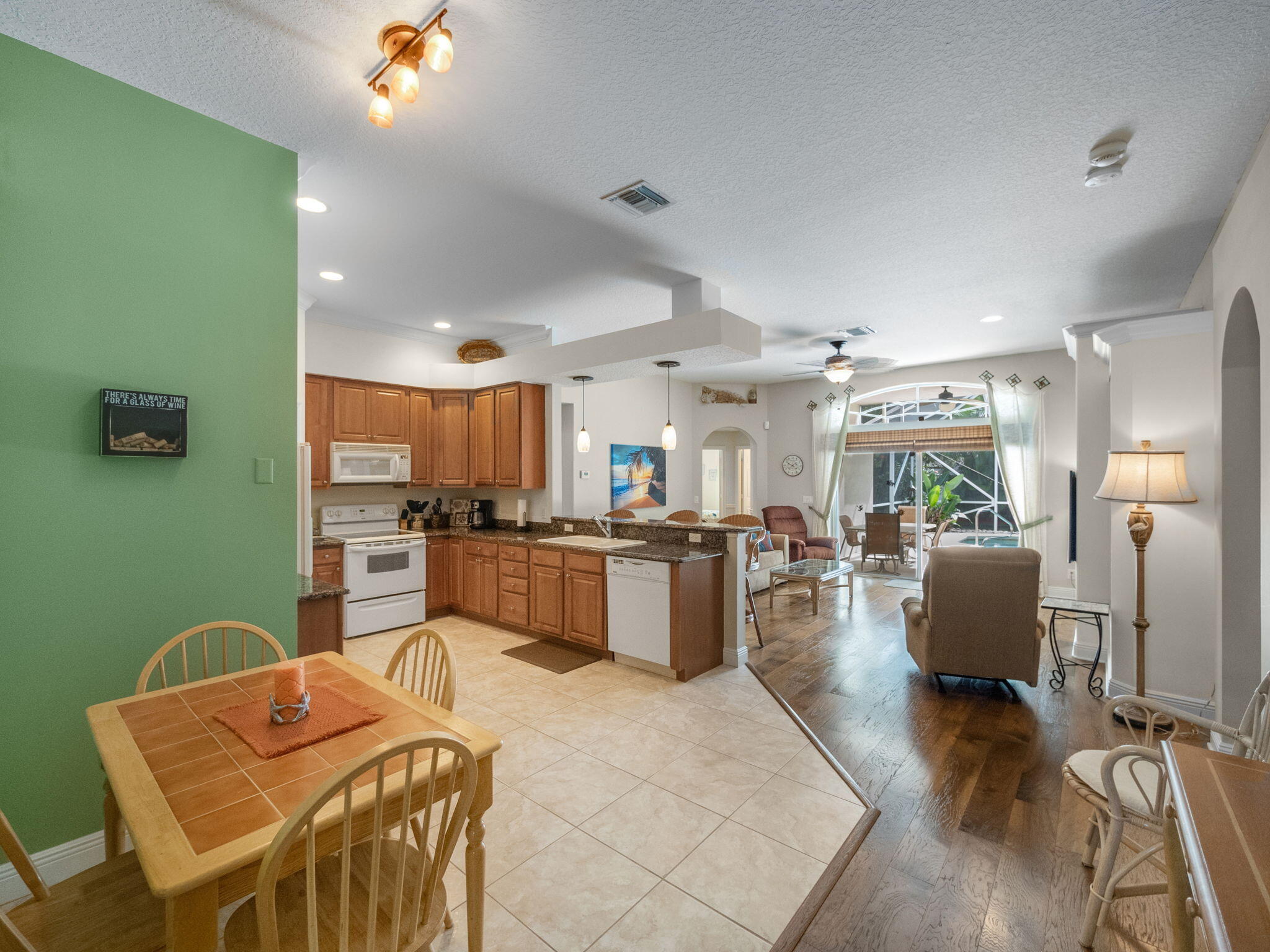 204 Clocktower Drive Jupiter, FL 33458 - Photo 6 of 21 a kitchen with stainless steel appliances kitchen island granite countertop a dining table chairs and a refrigerator