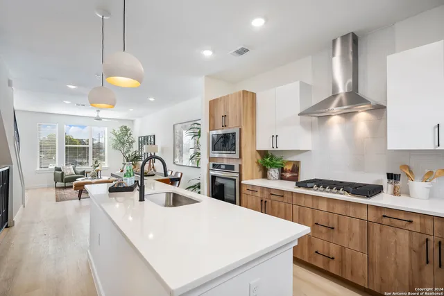 a kitchen with stainless steel appliances granite countertop a sink a stove and a wooden floors
