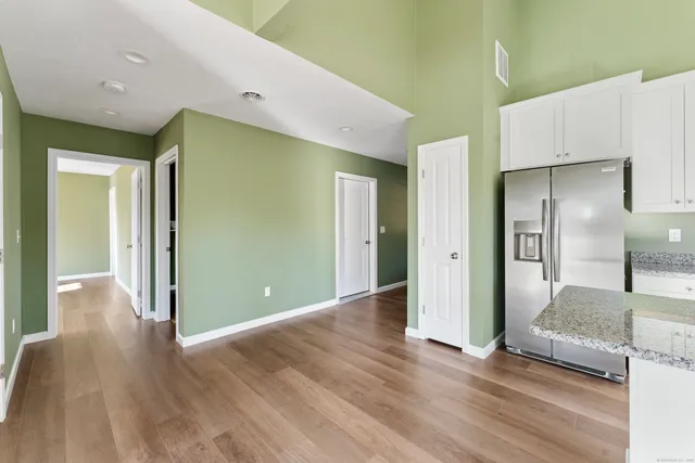 a view of a hallway with wooden floor and a bathroom