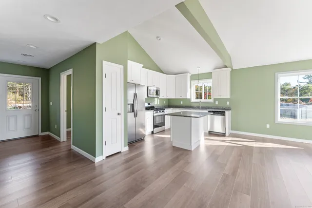 a kitchen with stainless steel appliances granite countertop a refrigerator a sink dishwasher and a stove with wooden floor