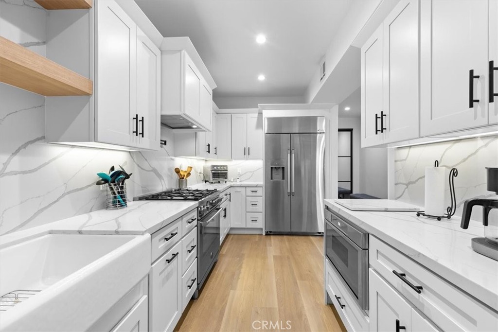 a kitchen with stainless steel appliances sink stove refrigerator and cabinets