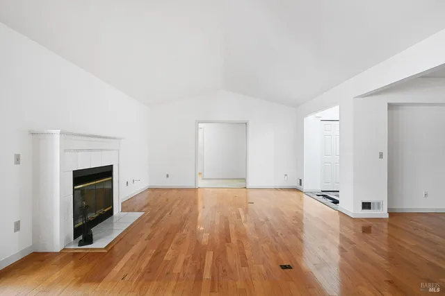 a view of empty room with wooden floor and fireplace