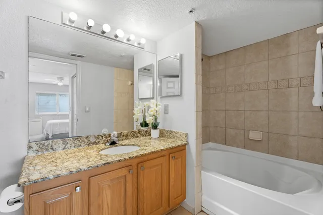 a bathroom with a granite countertop sink mirror and a bath tub