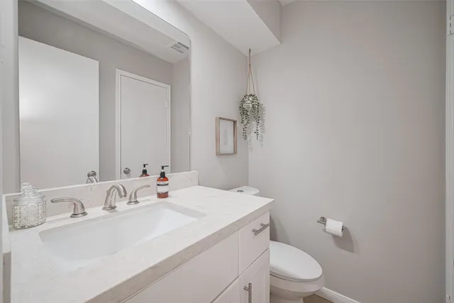 a bathroom with a sink vanity mirror and toilet