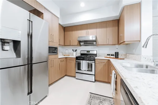 a kitchen with stainless steel appliances granite countertop white cabinets sink and a refrigerator