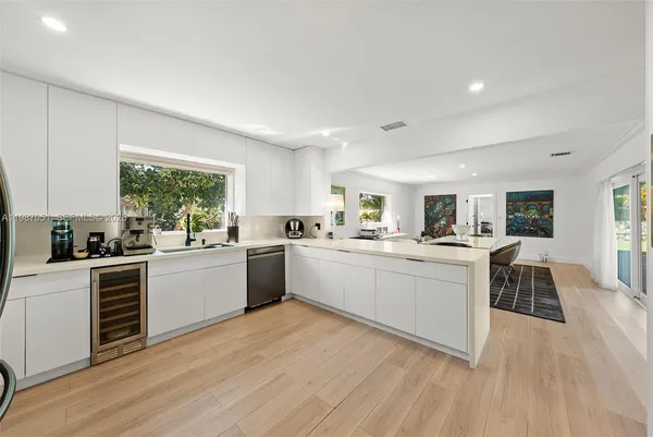 a kitchen with stainless steel appliances a dining table chairs and a refrigerator