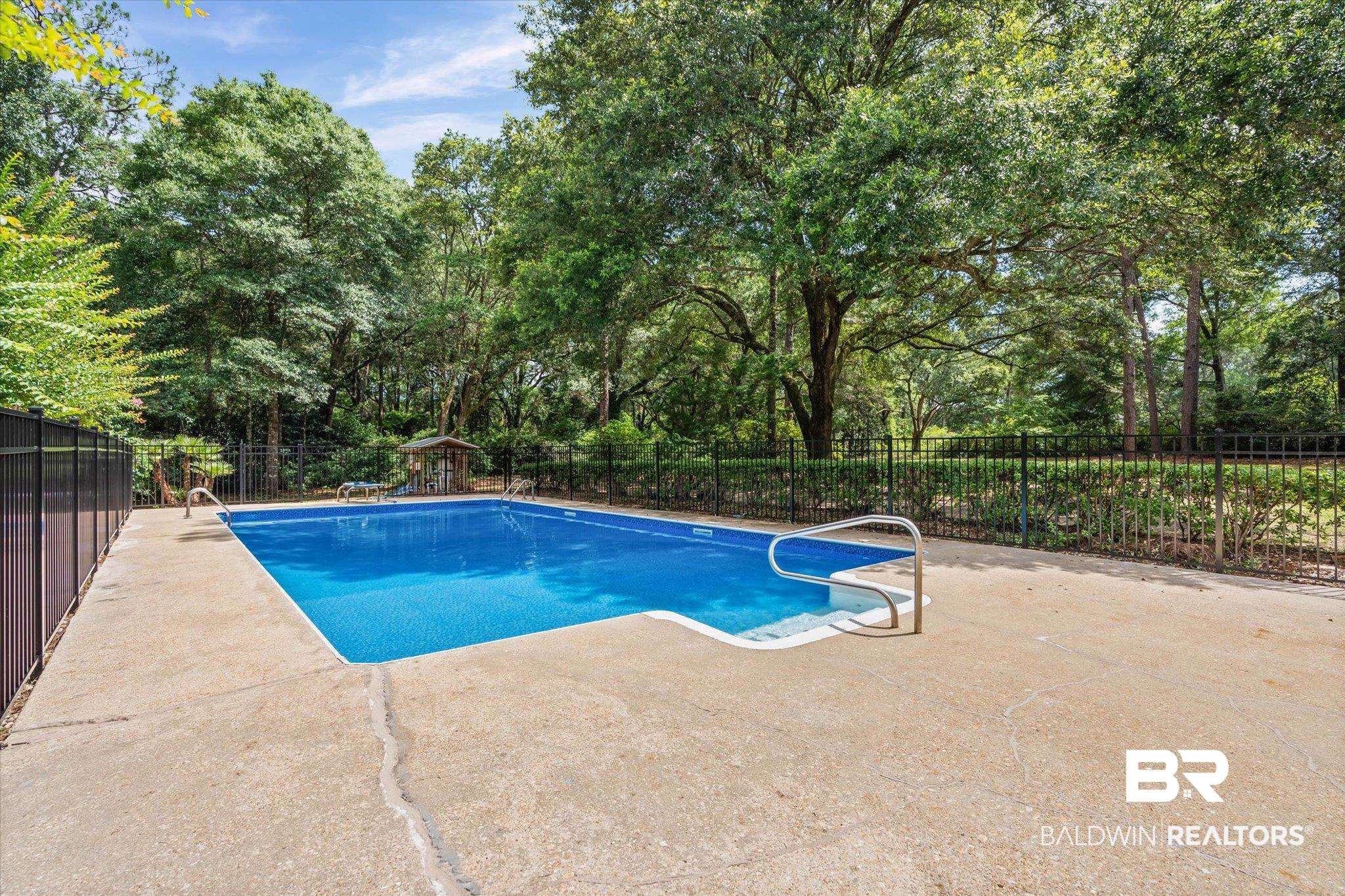 8301 Fordham Road Mobile, AL 36619 - Photo 29 of 57 Rectangular in-ground pool with concrete surround and surrounding black metal fencing