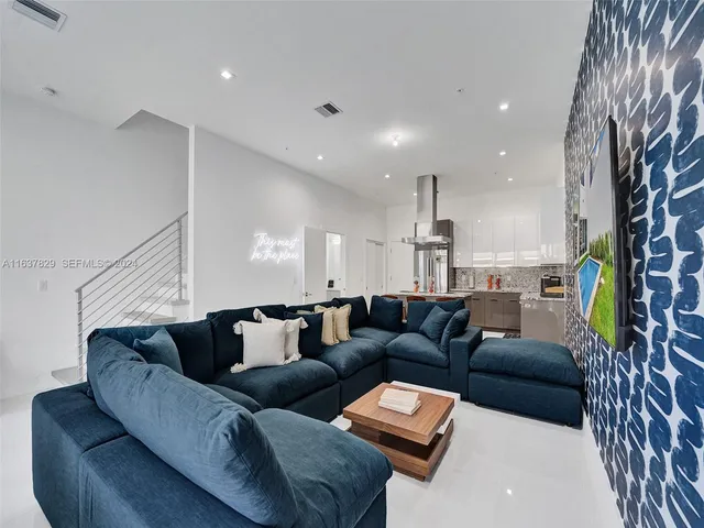 a living room with furniture a table and kitchen view