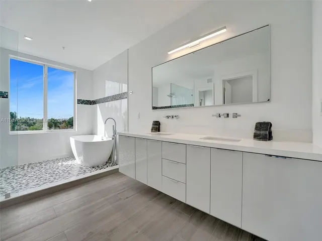 a living room with furniture a large window and wooden floor