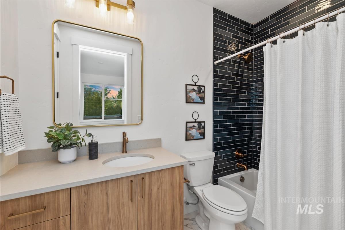 3219 West Moore Street Boise, ID 83702 - Photo 32 of 36 Bathroom featuring a wood-finish vanity with an undermount sink, a light-toned countertop, and a rectangular mirror