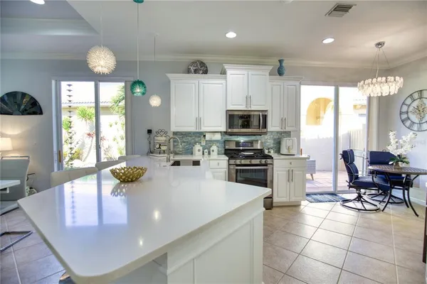 a kitchen with stainless steel appliances kitchen island granite countertop a sink a stove a microwave a dining table and chairs