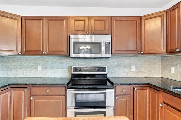 a kitchen with granite countertop wood cabinets and stainless steel appliances