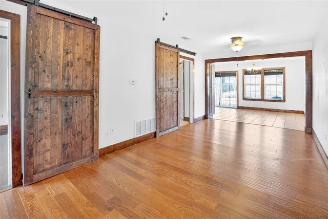 a view of an empty room with window and wooden floor