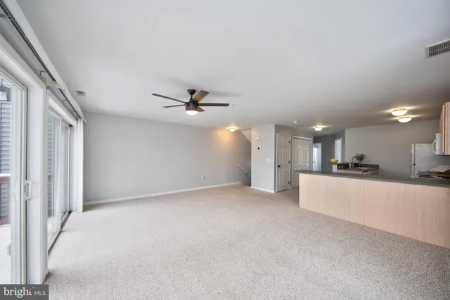 a view of a big room with chandelier fan and windows