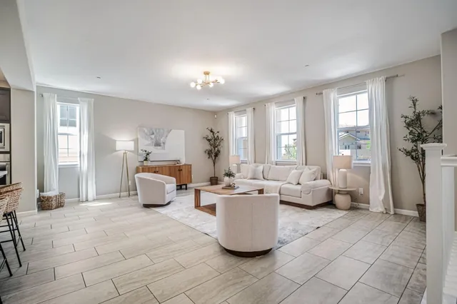 a living room with couches and kitchen view with wooden floor