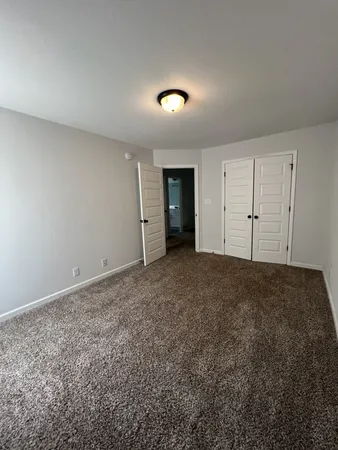 an empty room with a chandelier fan and windows