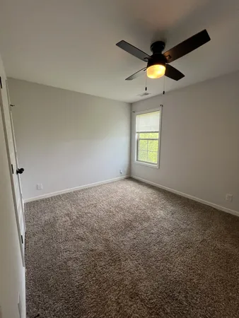 an empty room with a ceiling fan and a window