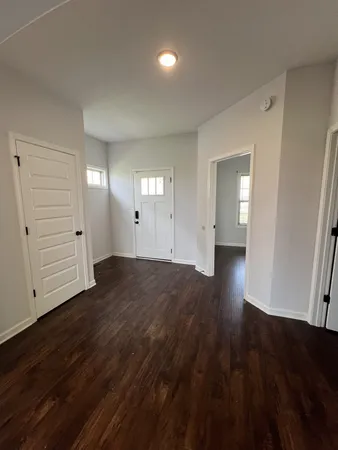 a view of an empty room with wooden floor and window
