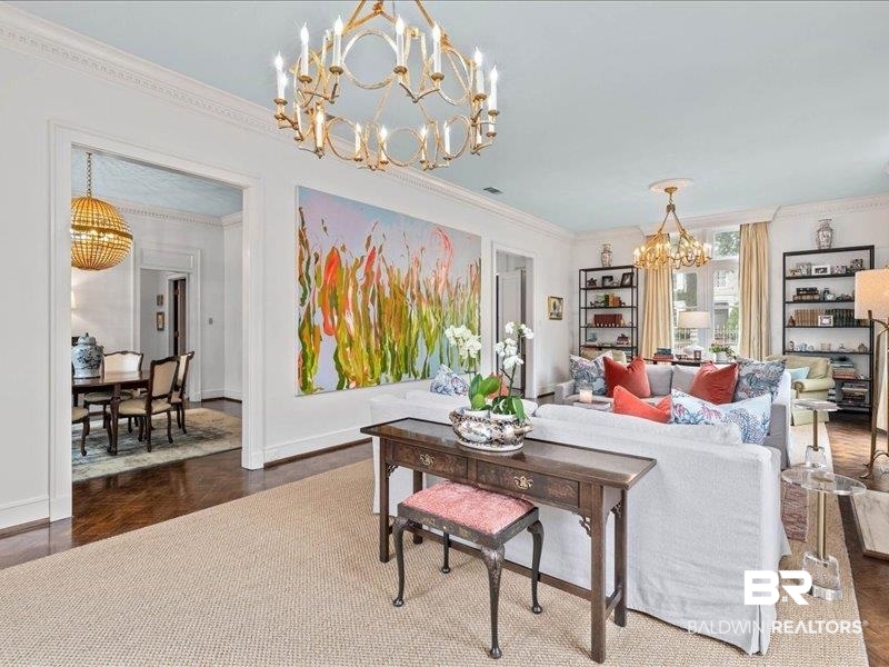 109 Eaton Square Mobile, AL 36608 - Photo 6 of 26 Spacious living area featuring two ornate brass chandeliers, crown molding, and light-toned wall finishes