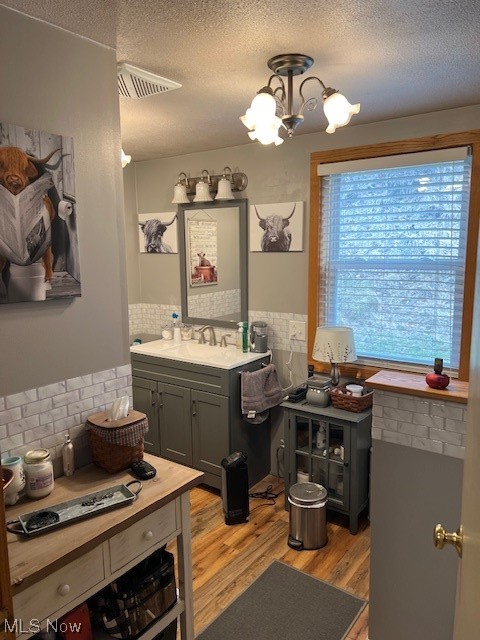 2855 Long Run Road Cairo, WV 26337 - Photo 12 of 25 Bathroom featuring vanity, a textured ceiling, hardwood / wood-style flooring, a notable chandelier, and backsplash